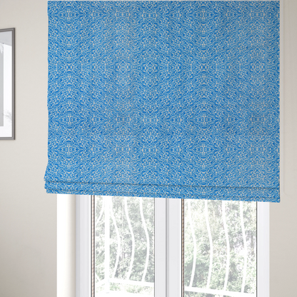 The fabric used to create these Roman blinds is a symmetrical, kaleidoscopic textile pattern in bright azure blue and white. The design features intricate, interlocking organic shapes mirrored vertically and horizontally to create a dense, mosaic-like filigree across the fabric.