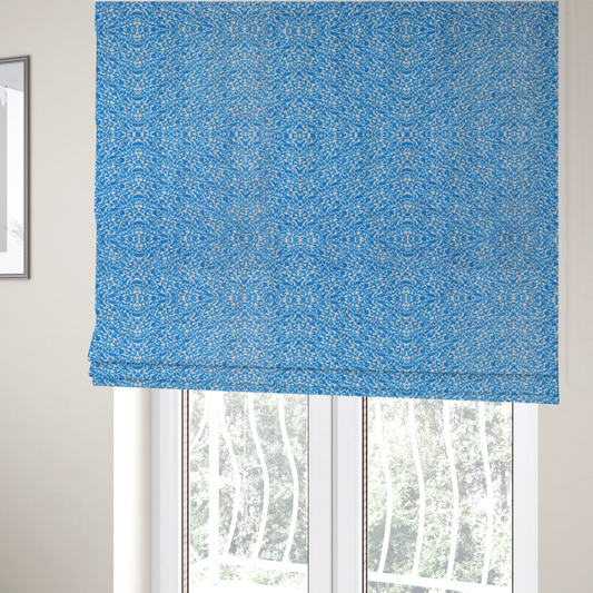 The fabric used to create these Roman blinds is a symmetrical, kaleidoscopic textile pattern in bright azure blue and white. The design features intricate, interlocking organic shapes mirrored vertically and horizontally to create a dense, mosaic-like filigree across the fabric.