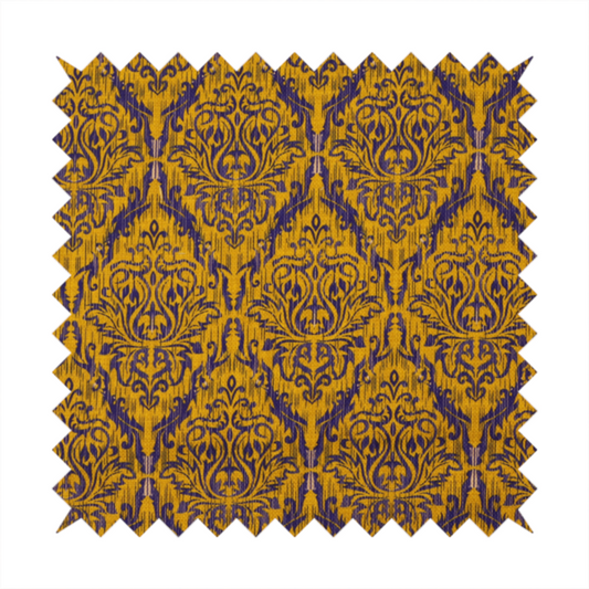 This fabric features a royal blue damask pattern layered over a deep mustard gold background. The design has an ikat-inspired finish, with vertical, feathered edges that give the ornate fleur-de-lis motifs a slightly blurred, textured appearance.