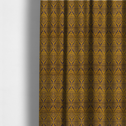 The fabric used to create these made-to-measure curtains features a royal blue damask pattern layered over a deep mustard gold background. The design has an ikat-inspired finish, with vertical, feathered edges that give the ornate fleur-de-lis motifs a slightly blurred, textured appearance.