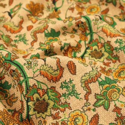 A vintage-style fabric featuring winding green vines and various floral blossoms in shades of orange, gold, and yellow. The pattern is set against a light beige, canvas-textured background, with a bohemian or arts-and-crafts aesthetic.