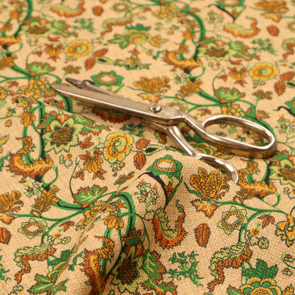 A vintage-style fabric featuring winding green vines and various floral blossoms in shades of orange, gold, and yellow. The pattern is set against a light beige, canvas-textured background, with a bohemian or arts-and-crafts aesthetic.