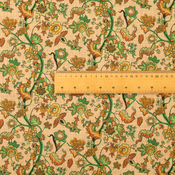 A vintage-style fabric featuring winding green vines and various floral blossoms in shades of orange, gold, and yellow. The pattern is set against a light beige, canvas-textured background, with a bohemian or arts-and-crafts aesthetic.