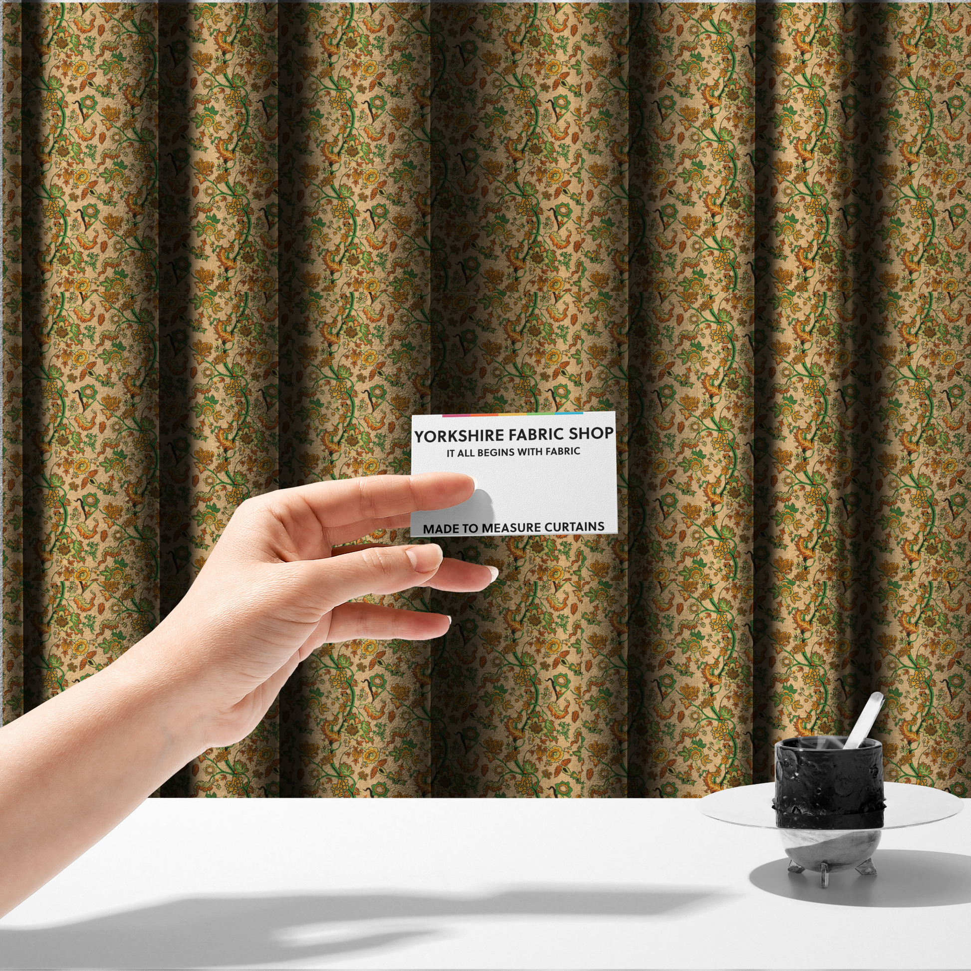 The fabric used to create these made-to-measure curtains is a vintage-style fabric featuring winding green vines and various floral blossoms in shades of orange, gold, and yellow. The pattern is set against a light beige, canvas-textured background, with a bohemian or arts-and-crafts aesthetic.