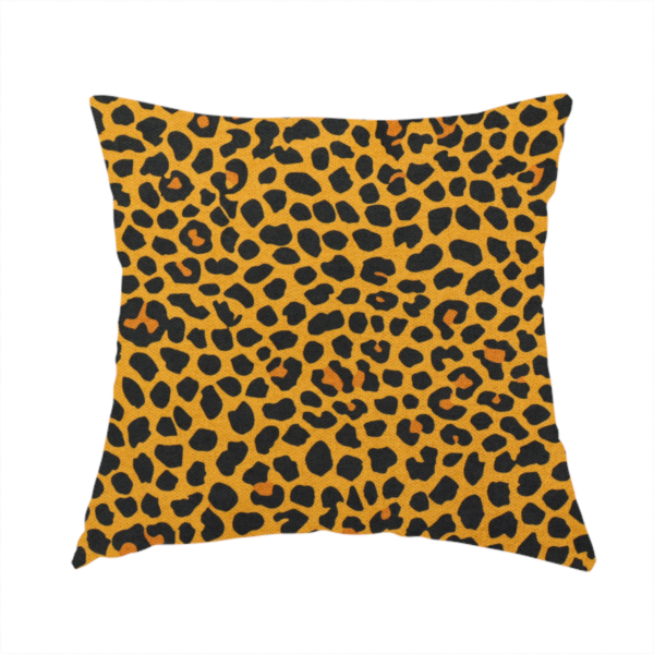 The fabric used to create this handmade cushion is a high-contrast animal print fabric featuring a dense leopard-inspired pattern. The design consists of irregular black spots and open rosettes with warm orange-brown centres, set against a vibrant mustard-yellow background. The print is small-scale and tightly packed, with a visible fine-grained textile texture