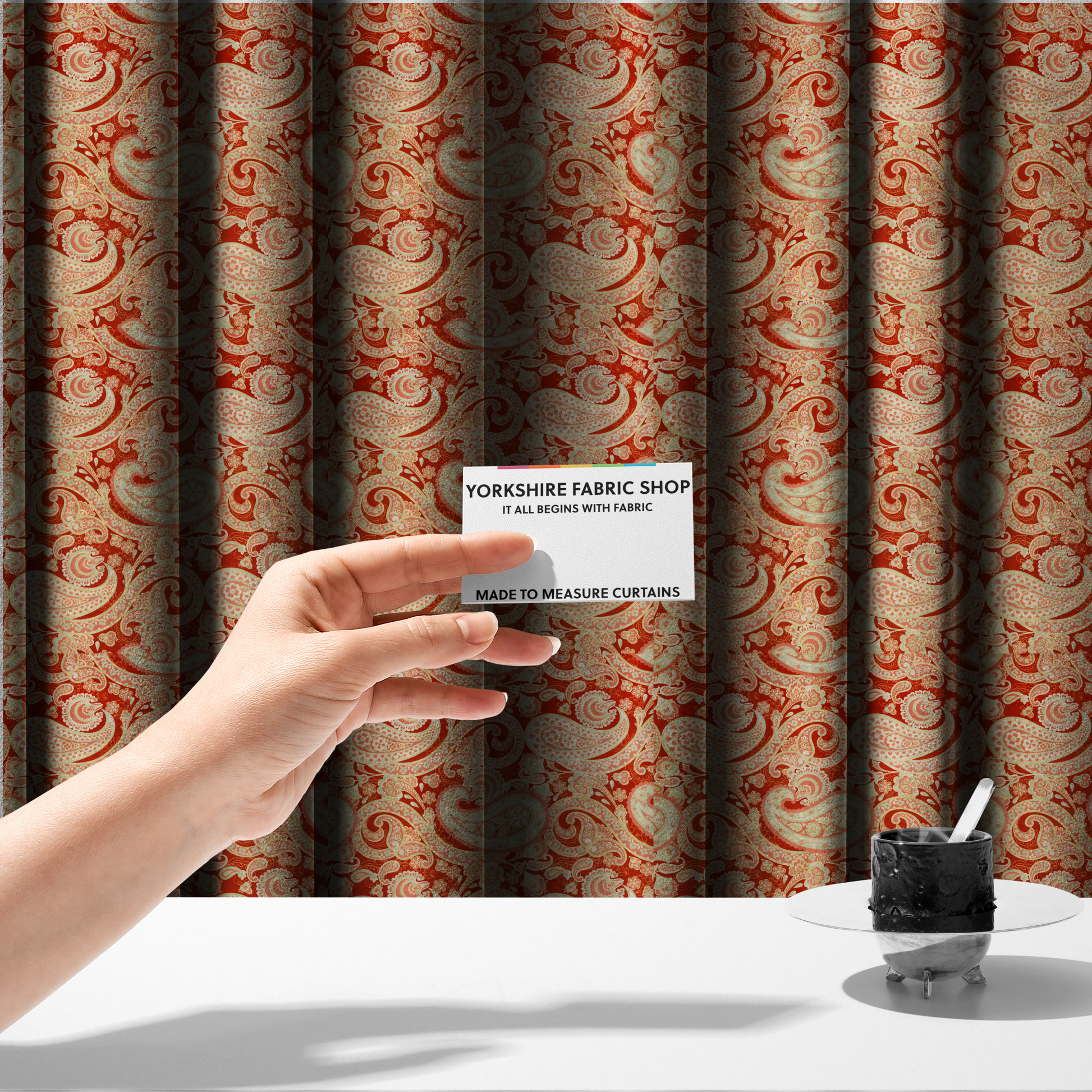 The fabric used to create these made-to-measure curtains is a vibrant, warm-toned textile featuring large-scale paisley teardrop motifs in shades of cream, pale mint, and soft orange against a bold red background. The intricate patterns within the paisley shapes include delicate floral borders and internal mandalas, surrounded by smaller scattered flower accents for a rich, traditional Indian-inspired aesthetic.