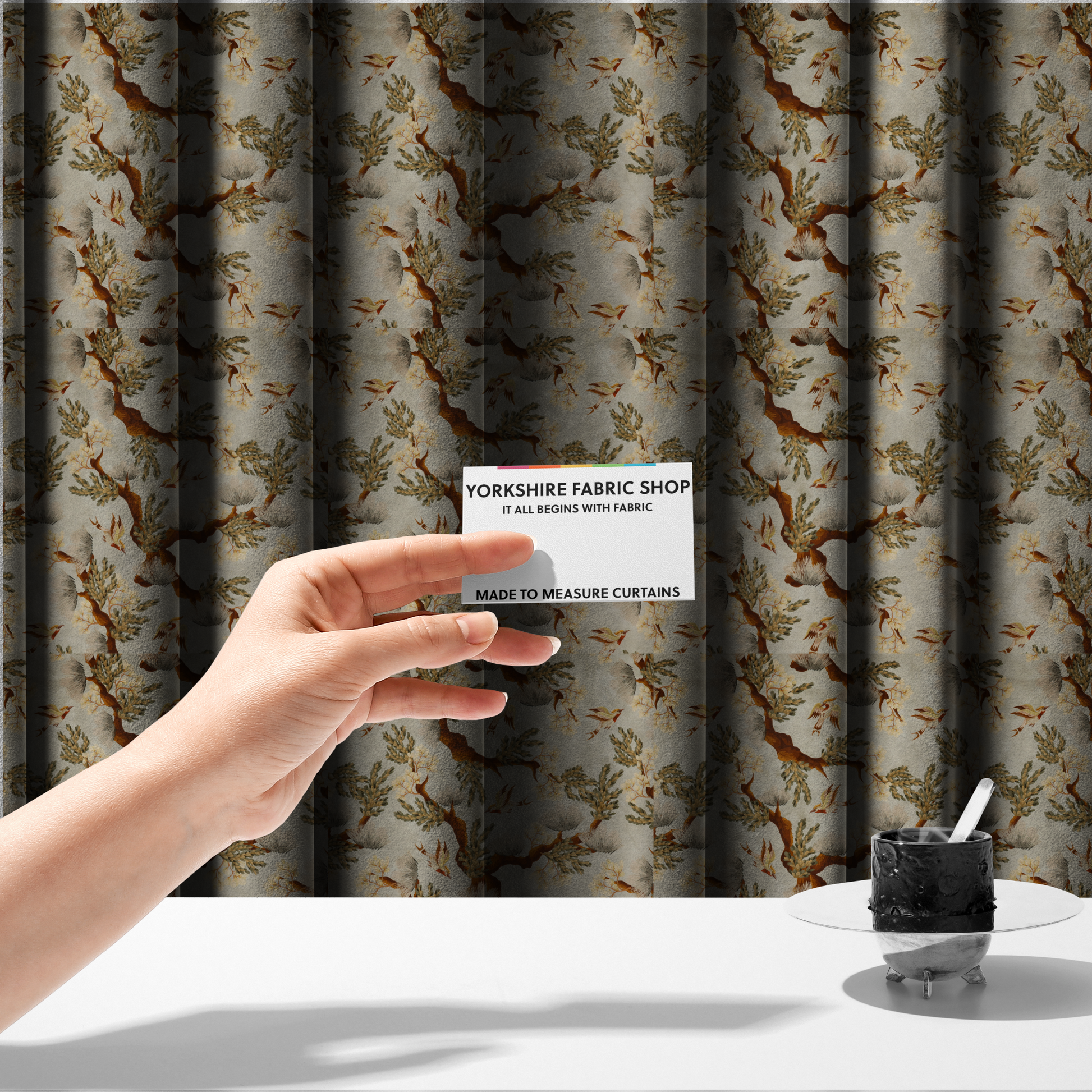 The fabric used to create these made-to-measure curtains is a sophisticated textile featuring a Chinoiserie-style pattern with stylized birds in flight among winding, dark brown tree branches. The branches are adorned with clusters of pale cream blossoms and soft, pine-like needles. The entire design is set against a muted beige background creating a serene and classical aesthetic.