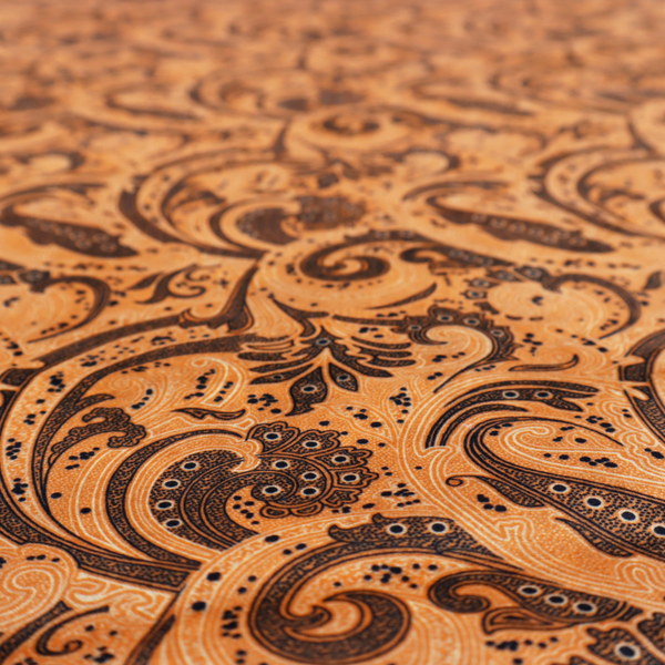 A complex textile design featuring an all-over paisley and scroll pattern in solid black over a warm copper-orange background. The motifs are highly stylized with a mixture of dotted textures, fine line work, and bold curves that resemble ocean waves or flowing vines. The high-contrast colour palette gives the fabric a sophisticated, bohemian-luxe appearance.