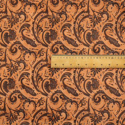 A complex textile design featuring an all-over paisley and scroll pattern in solid black over a warm copper-orange background. The motifs are highly stylized with a mixture of dotted textures, fine line work, and bold curves that resemble ocean waves or flowing vines. The high-contrast colour palette gives the fabric a sophisticated, bohemian-luxe appearance.