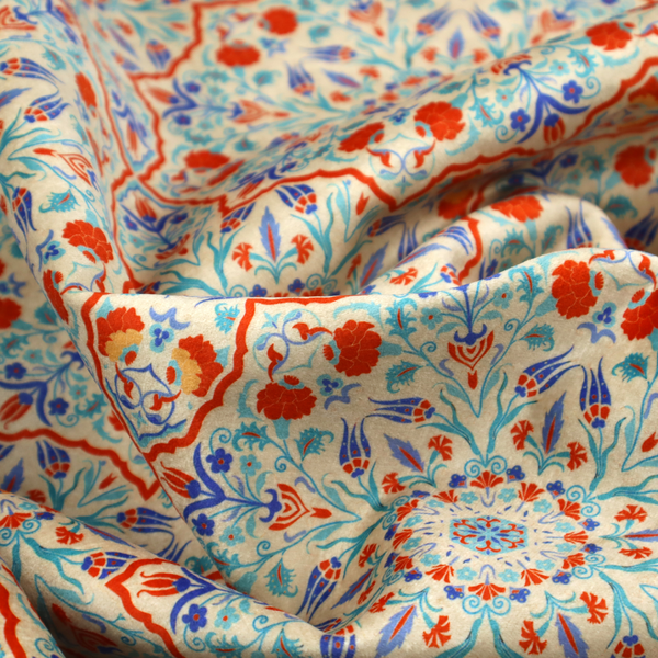 A decorative fabric with an Ottoman-style floral print. The design consists of repeating cobalt blue and turquoise tulips and deep red carnations intertwined with long, curving green leaves. The pattern mimics 16th-century Mediterranean ceramic tile art.
