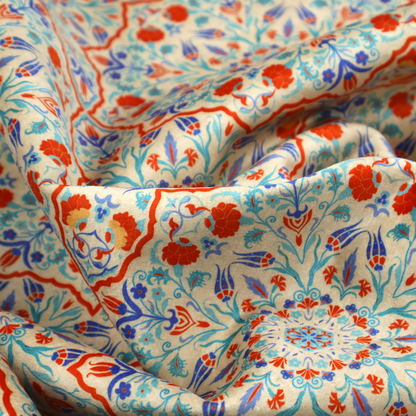 A decorative fabric with an Ottoman-style floral print. The design consists of repeating cobalt blue and turquoise tulips and deep red carnations intertwined with long, curving green leaves. The pattern mimics 16th-century Mediterranean ceramic tile art.