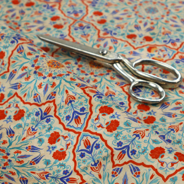 A decorative fabric with an Ottoman-style floral print. The design consists of repeating cobalt blue and turquoise tulips and deep red carnations intertwined with long, curving green leaves. The pattern mimics 16th-century Mediterranean ceramic tile art.