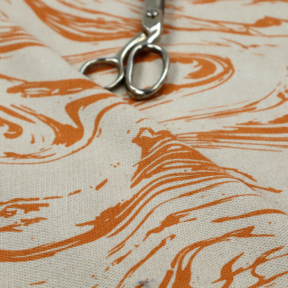 Abstract marbled fabric featuring fluid, organic swirls in a warm burnt orange colour over a textured cream-colored background.