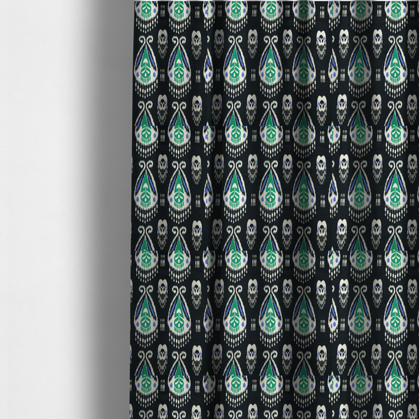 The fabric used to create these made-to-measure curtains is a dark textile featuring rows of floating, feathered ikat medallions. The design glows with emerald green and bright sapphire blue against a deep obsidian background, accented by crisp white geometric tassels and swirling crown-like scrollwork.