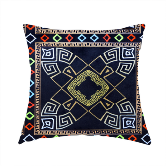 The fabric used to create this handmade cushion is a luxury black fabric featuring a structured gold Greek Key and geometric medallion pattern, bordered by a vibrant row of small neon red, green, and blue diamond shapes.