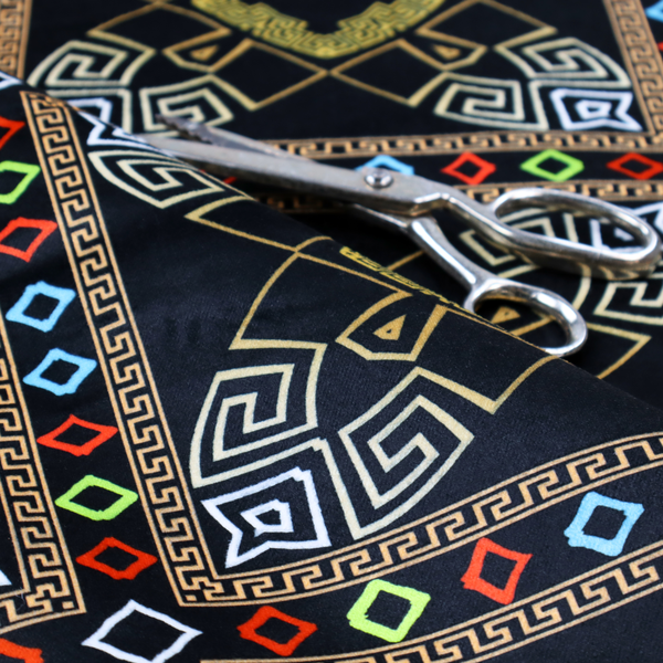 Luxury black fabric featuring a structured gold Greek Key and geometric medallion pattern, bordered by a vibrant row of small neon red, green, and blue diamond shapes.