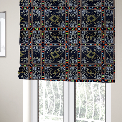 The fabric used to create these Roman blinds is a luxury black fabric featuring a structured gold Greek Key and geometric medallion pattern, bordered by a vibrant row of small neon red, green, and blue diamond shapes.