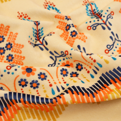 Folk-art style fabric featuring horizontal rows of stylized orange and navy floral pillars and geometric chevron borders on a warm cream background