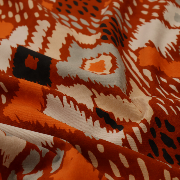 Bohemian ikat fabric featuring a dense diamond pattern in burnt orange, cream, and charcoal black with distressed, hand-stamped textures.