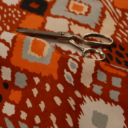 Bohemian ikat fabric featuring a dense diamond pattern in burnt orange, cream, and charcoal black with distressed, hand-stamped textures.