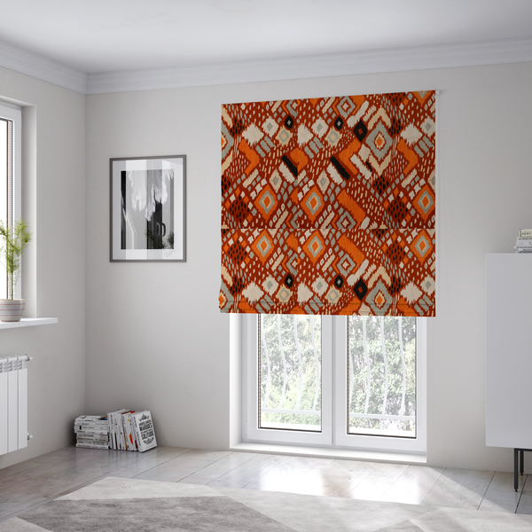 The fabric used to create these Roman blinds is a bohemian ikat fabric featuring a dense diamond pattern in burnt orange, cream, and charcoal black with distressed, hand-stamped textures.