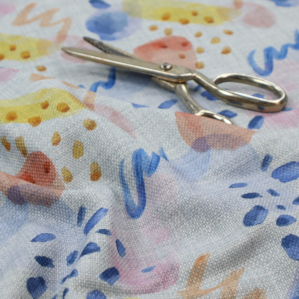 Abstract watercolour pattern of blue, ochre, and peach shapes with squiggly lines and navy dots on a light grey linen-textured background.
