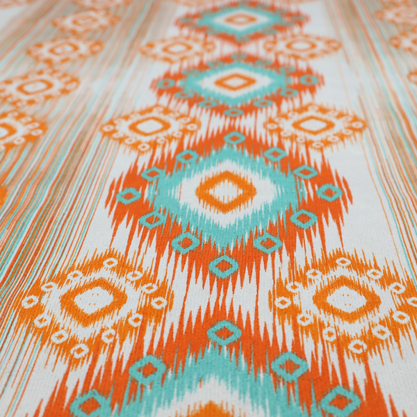 A striking geometric fabric featuring vibrant diamond medallions with blurred, ikat-style edges layered over a dynamic pattern of fine vertical streaks on a light background.
