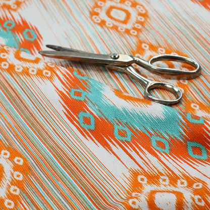 A striking geometric fabric featuring vibrant diamond medallions with blurred, ikat-style edges layered over a dynamic pattern of fine vertical streaks on a light background.