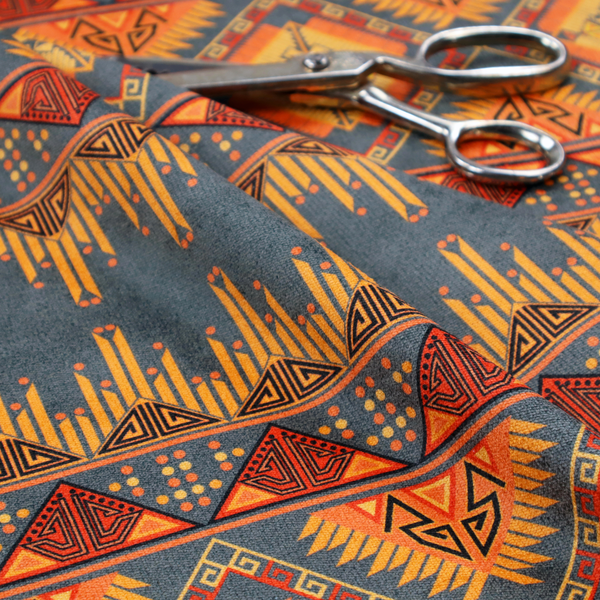 A detailed geometric fabric featuring tiered horizontal bands of intricate diamond motifs, zig-zag patterns, and sharp tribal-style linework in warm, sun-drenched tones.