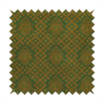 A repeating, decorative fabric pattern featuring ornate, gold-toned paisley motifs centred on a deep forest green background. The design is structured around a subtle lattice of small, delicate floral sprigs, creating a traditional, block-printed aesthetic with a slightly weathered, vintage texture.