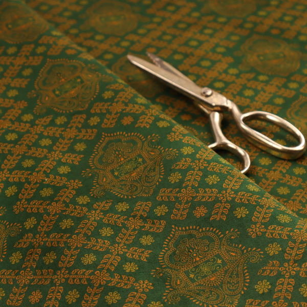 A repeating, decorative fabric pattern featuring ornate, gold-toned paisley motifs centred on a deep forest green background. The design is structured around a subtle lattice of small, delicate floral sprigs, creating a traditional, block-printed aesthetic with a slightly weathered, vintage texture.