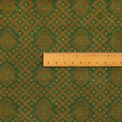 A repeating, decorative fabric pattern featuring ornate, gold-toned paisley motifs centred on a deep forest green background. The design is structured around a subtle lattice of small, delicate floral sprigs, creating a traditional, block-printed aesthetic with a slightly weathered, vintage texture.