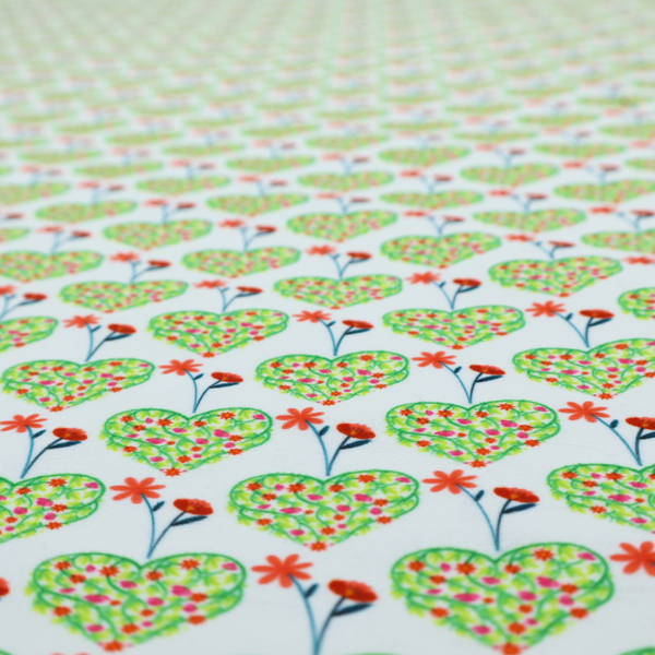 This fabric shows a repeating pattern on a light blue-grey background. The pattern consists of rows of heart shapes made of green vines and small pink and red flowers. Each heart is topped with a red flower on a thin blue stem and flanked by another red flower on its own blue stem. These floral elements repeat across the entire fabric.