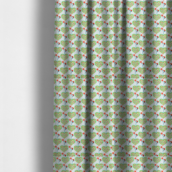 The fabric used to create these made-to-measure curtains is a repeating pattern on a light blue-grey background. The pattern consists of rows of heart shapes made of green vines and small pink and red flowers. Each heart is topped with a red flower on a thin blue stem and flanked by another red flower on its own blue stem. These floral elements repeat across the entire fabric.