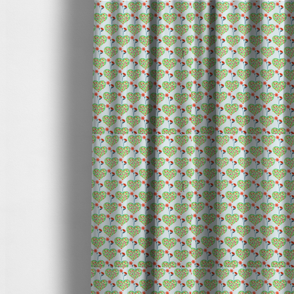 The fabric used to create these made-to-measure curtains is a repeating pattern on a light blue-grey background. The pattern consists of rows of heart shapes made of green vines and small pink and red flowers. Each heart is topped with a red flower on a thin blue stem and flanked by another red flower on its own blue stem. These floral elements repeat across the entire fabric.