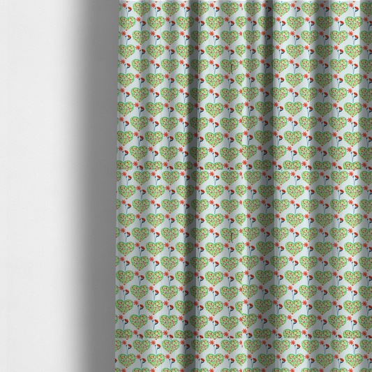 The fabric used to create these made-to-measure curtains is a repeating pattern on a light blue-grey background. The pattern consists of rows of heart shapes made of green vines and small pink and red flowers. Each heart is topped with a red flower on a thin blue stem and flanked by another red flower on its own blue stem. These floral elements repeat across the entire fabric.