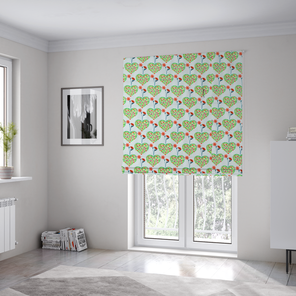 The fabric used to create these Roman blinds is a repeating pattern on a light blue-grey background. The pattern consists of rows of heart shapes made of green vines and small pink and red flowers. Each heart is topped with a red flower on a thin blue stem and flanked by another red flower on its own blue stem. These floral elements repeat across the entire fabric.