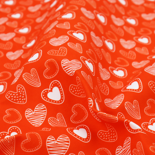 This vibrant red fabric features a playful, repeating pattern of white heart illustrations. The hearts are hand-drawn in several distinct styles, including solid outlines with dotted borders, sketched diagonal stripes, and intricate stippled patterns. These varied heart motifs are scattered across the bright background at different angles, creating a lively and energetic design.