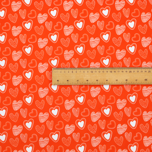 This vibrant red fabric features a playful, repeating pattern of white heart illustrations. The hearts are hand-drawn in several distinct styles, including solid outlines with dotted borders, sketched diagonal stripes, and intricate stippled patterns. These varied heart motifs are scattered across the bright background at different angles, creating a lively and energetic design.