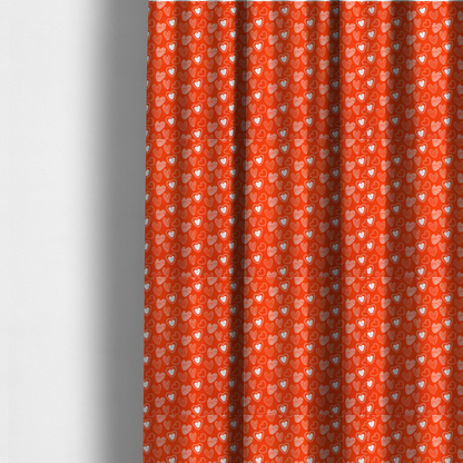 The fabric used to create these made-to-measure curtains is a vibrant red fabric features a playful, repeating pattern of white heart illustrations. The hearts are hand-drawn in several distinct styles, including solid outlines with dotted borders, sketched diagonal stripes, and intricate stippled patterns. These varied heart motifs are scattered across the bright background at different angles, creating a lively and energetic design.