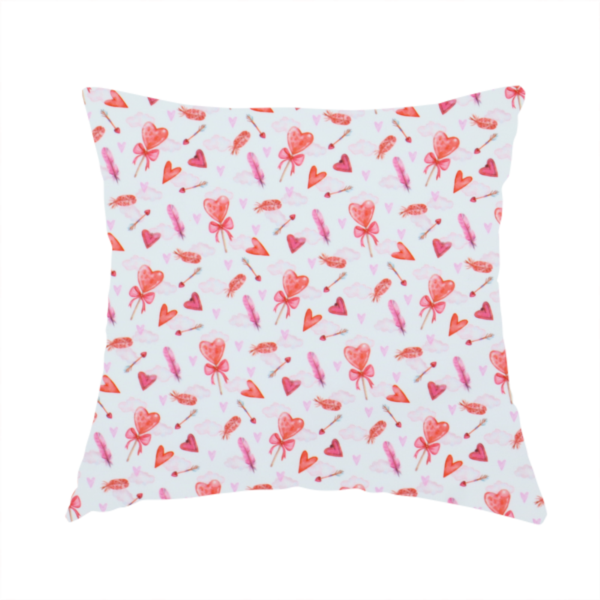 The fabric used to create this handmade cushion is a white fabric featuring a light, whimsical Valentine’s Day pattern with watercolour elements scattered across a pale background. The design includes pink heart-shaped balloons tied with bows, soft pink feathers, and various small arrows and hearts. Faint, dreamy cloud-like textures in pink and blue are visible in the background, adding to the soft, airy aesthetic.