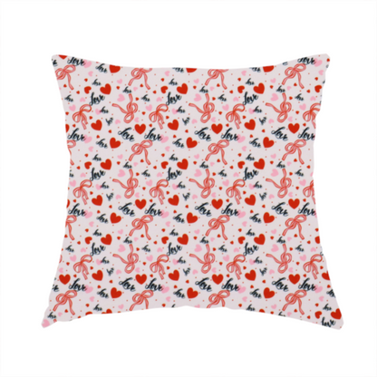 The fabric used for this handmade cushion is a light pink fabric featuring a dense, repeating Valentine’s Day pattern with a vintage, romantic aesthetic. The design is composed of small red hearts and larger pink hearts, interspersed with delicate red ribbon bows and the word "love" written in a dark, flowing cursive script. Tiny red dots are scattered throughout the background, creating a textured, confetti-like effect across the entire print.