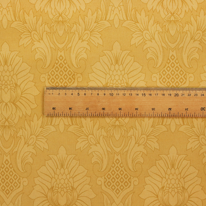 Luxurious tonal gold damask fabric featuring a repeating symmetrical floral medallion pattern in shimmering amber and matte ochre tones.