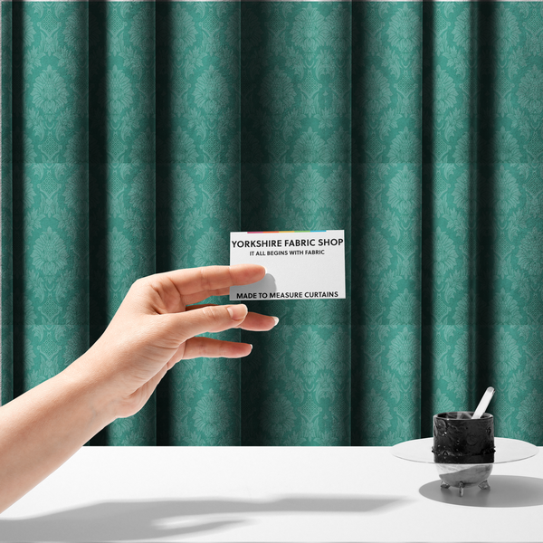 The fabric used to create these made-to-measure curtains is a vibrant teal damask fabric featuring a large-scale, repeating floral and acanthus leaf pattern in a tonal, monochromatic seafoam green colourway.