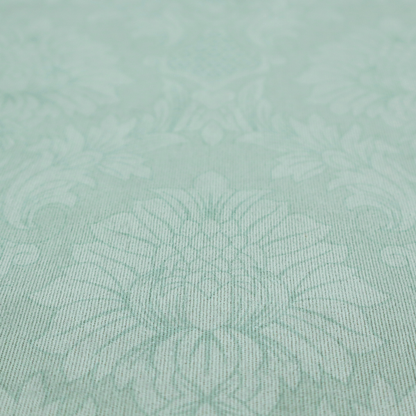 Pale ice blue damask fabric with a subtle, low-contrast floral medallion pattern in light pastel tones.