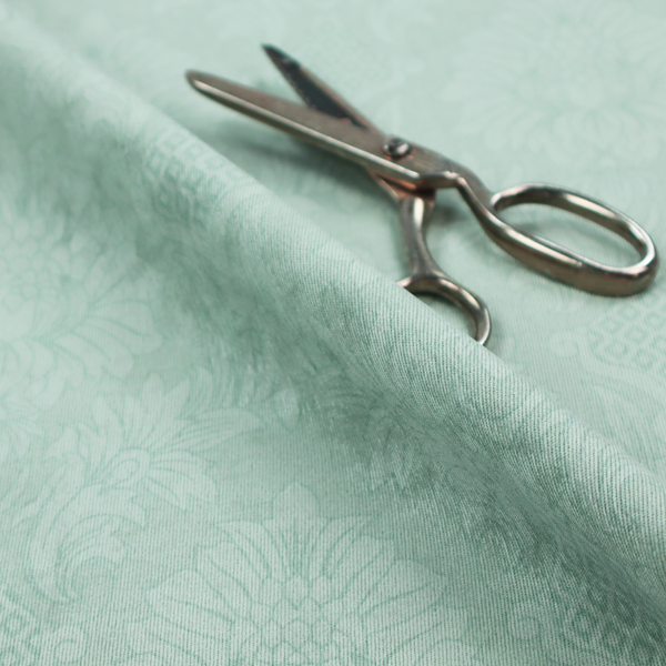 Pale ice blue damask fabric with a subtle, low-contrast floral medallion pattern in light pastel tones.