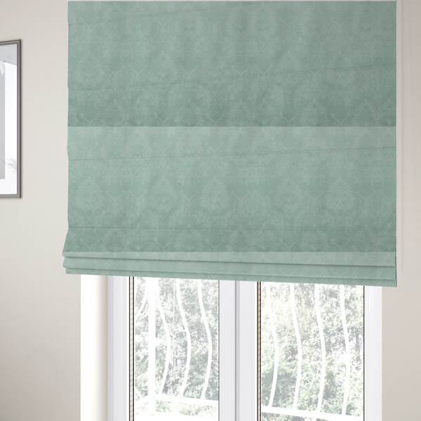 The fabric used to create these Roman blinds is a pale ice blue damask fabric with a subtle, low-contrast floral medallion pattern in light pastel tones.