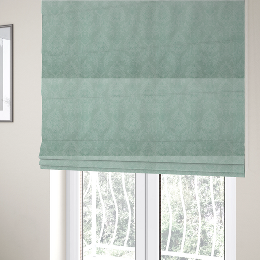 The fabric used to create these Roman blinds is a pale ice blue damask fabric with a subtle, low-contrast floral medallion pattern in light pastel tones.