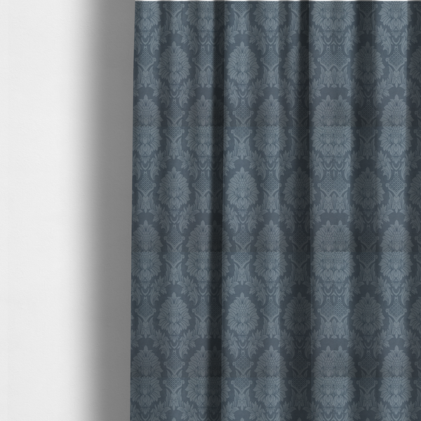 The fabric used to create these made-to-measure curtains is a sophisticated slate blue damask fabric featuring a large-scale, repeating floral and acanthus leaf pattern in a tonal, steel grey colourway.