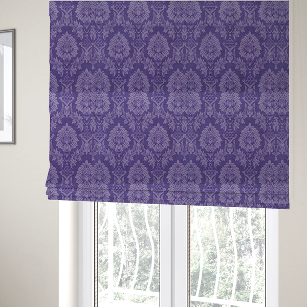 The fabric used to create these Roman blinds is a regal royal purple damask fabric featuring a large-scale, repeating floral and acanthus leaf pattern in a shimmering tonal violet colourway.